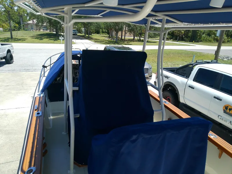 Slide: The Image of 1985 Robalo 2520 Center Console boat with blue covers, parked near white trucks. - 13
