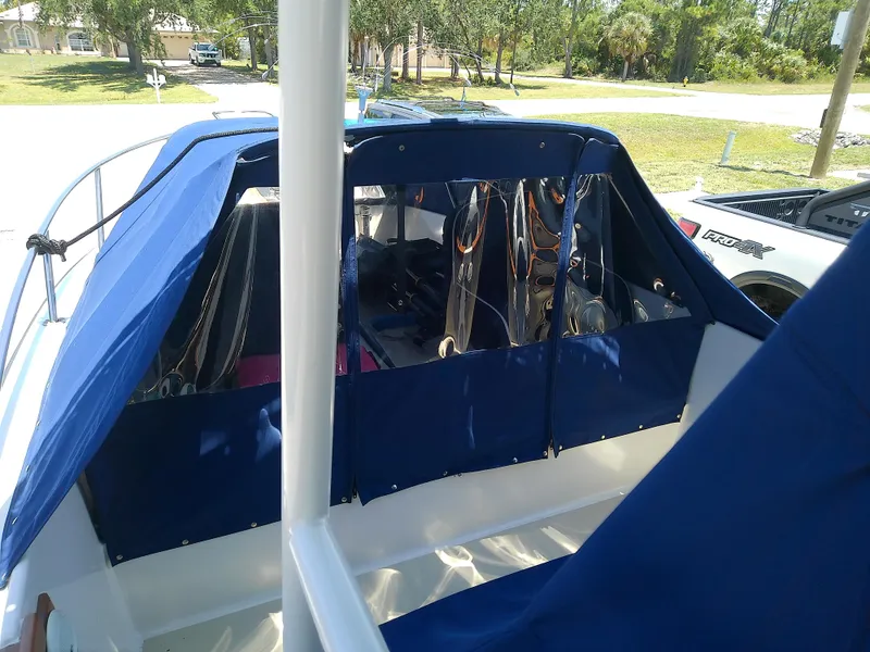 Slide: The Image of 1985 Robalo 2520 Center Console boat with blue canvas cover, parked outdoors. - 14