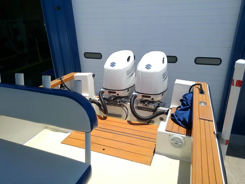 Slide: The Image of 1985 Robalo 2520 Center Console with twin outboard engines, docked near a blue building. - 22