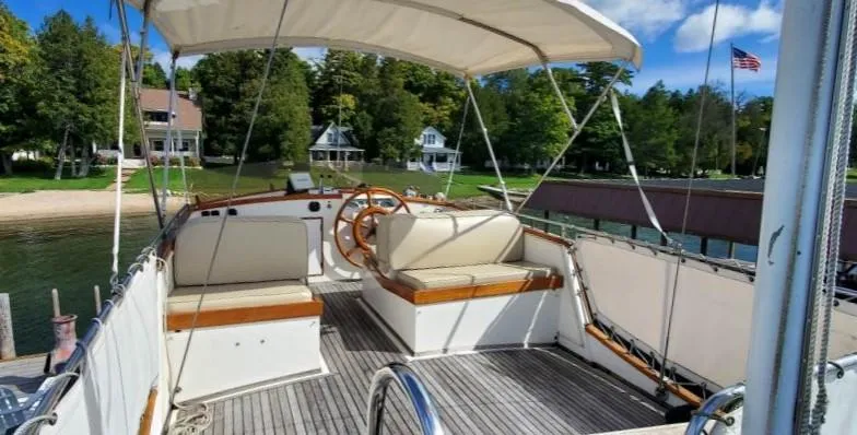 Slide: The Image of 1983 Grand Banks 36 Classic yacht deck with seating, docked near lush greenery and houses. - 4