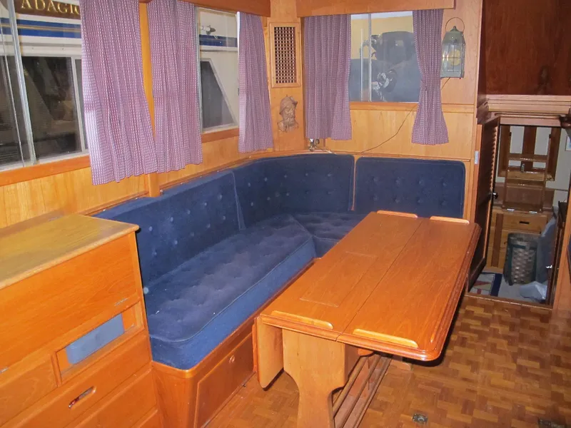 Slide: The Image of 1983 Grand Banks 36 Classic interior with blue seating, wooden table, and purple curtains. - 5