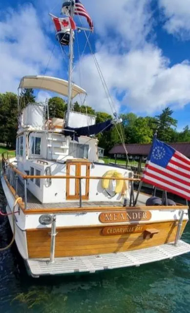 Slide: The Image of 1983 Grand Banks 36 Classic boat docked, displaying flags, under a clear blue sky. - 9
