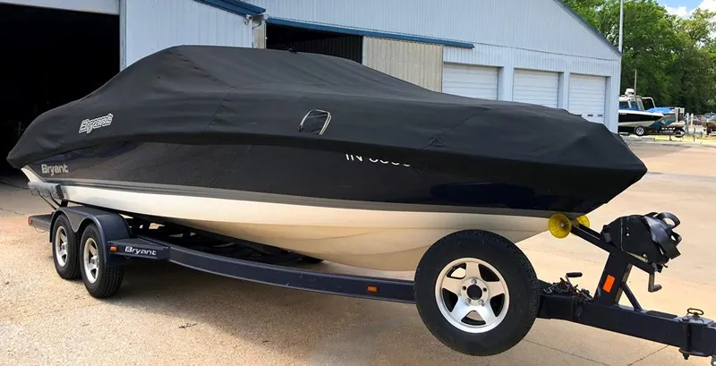 Slide: The Image of 2008 Bryant 246 BR boat on trailer, covered, parked near a building. - 13