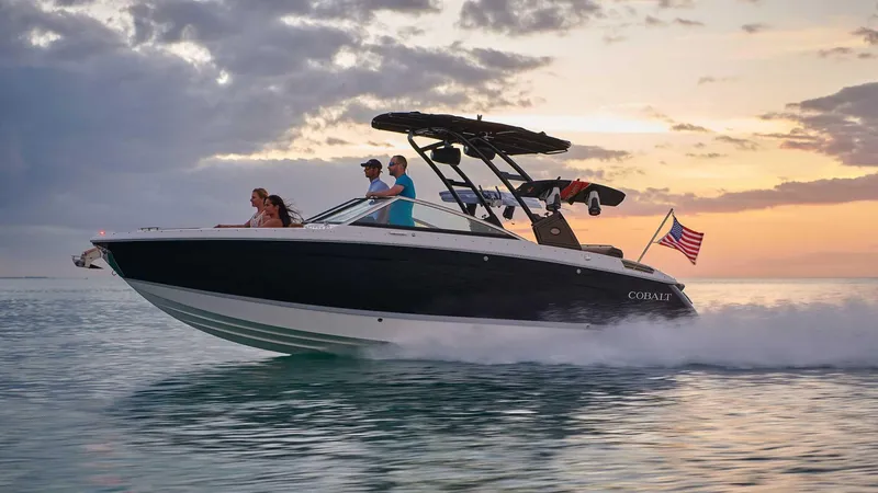 Slide: The Image of 2025 Cobalt R6 boat cruising at sunset with passengers, American flag waving. - 1