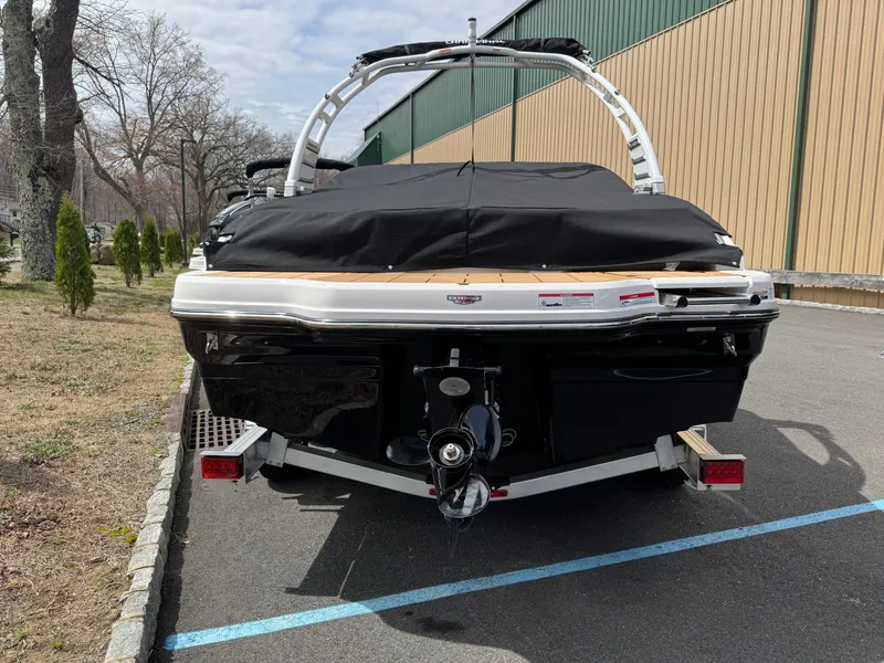 Slide: The Image of 2025 Chaparral 21 SSi boat, rear view, parked on a trailer, covered, outdoors. - 2