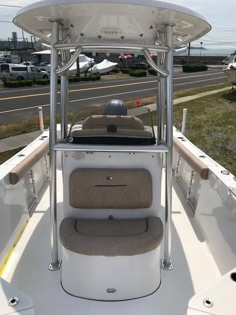 Slide: The Image of 2020 Sportsman Open 232 Center Console boat with seating and T-top, docked near a road. - 10