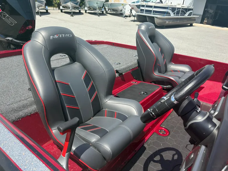 Slide: The Image of 2024 Nitro Z19 boat interior with sleek gray and red seats, steering wheel, and deck. - 7