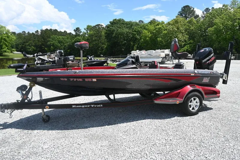 Slide: The Image of 2016 Ranger Z518 boat on trailer, parked outdoors on gravel, surrounded by trees. - 1