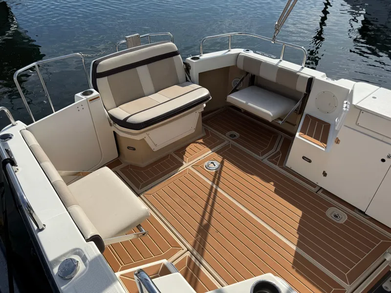 Slide: The Image of 2014 Cutwater C-28 Coupe boat deck with seating, featuring wood-style flooring and water backdrop. - 13