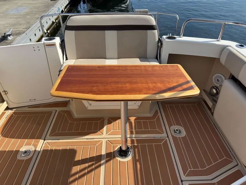 Slide: The Image of 2014 Cutwater C-28 Coupe boat deck with wooden table and seating. - 14