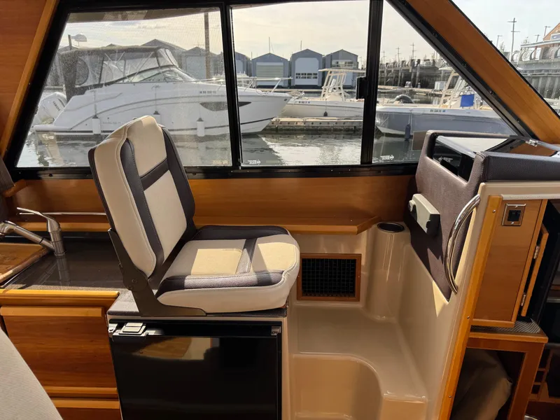 Slide: The Image of 2014 Cutwater C-28 Coupe interior with helm seat, window view of marina. - 20