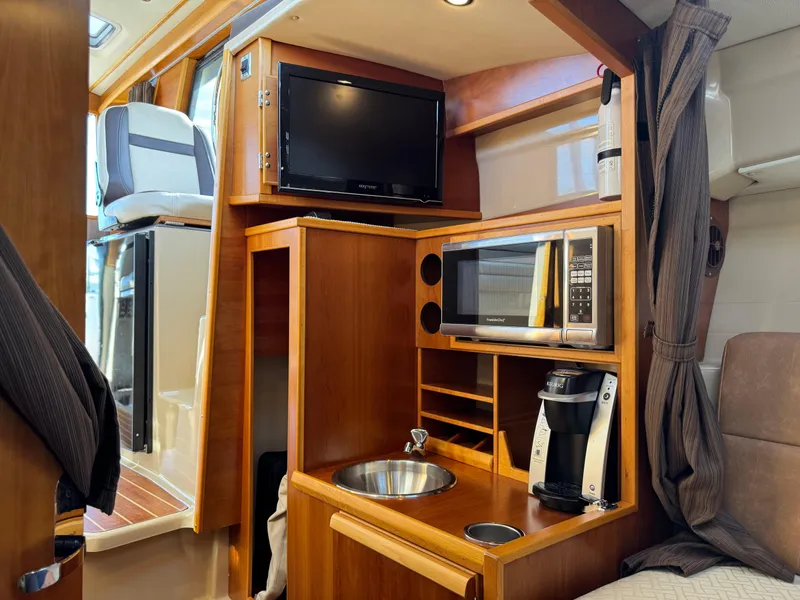 Slide: The Image of 2014 Cutwater C-28 Coupe interior with kitchenette, TV, microwave, and coffee maker. - 29