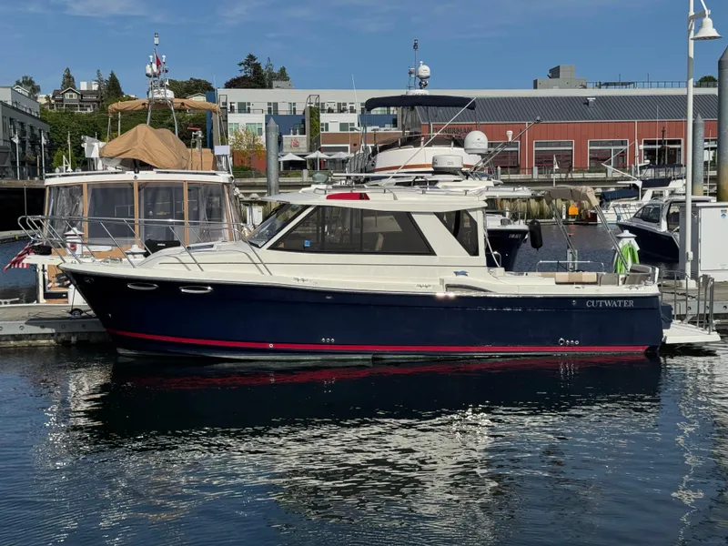 Slide: The Image of 2014 Cutwater C-28 Coupe boat docked at a marina, reflecting on calm water. - 3