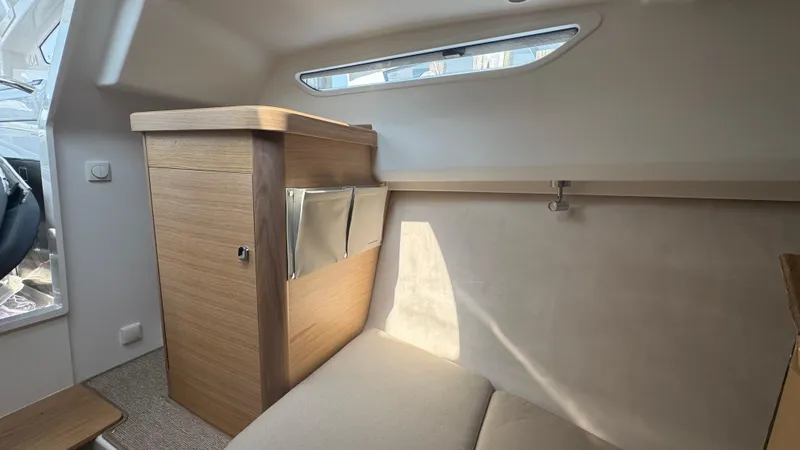 Slide: The Image of 2024 Nimbus W9 cabin interior with wooden cabinetry and seating, featuring natural light through window. - 17