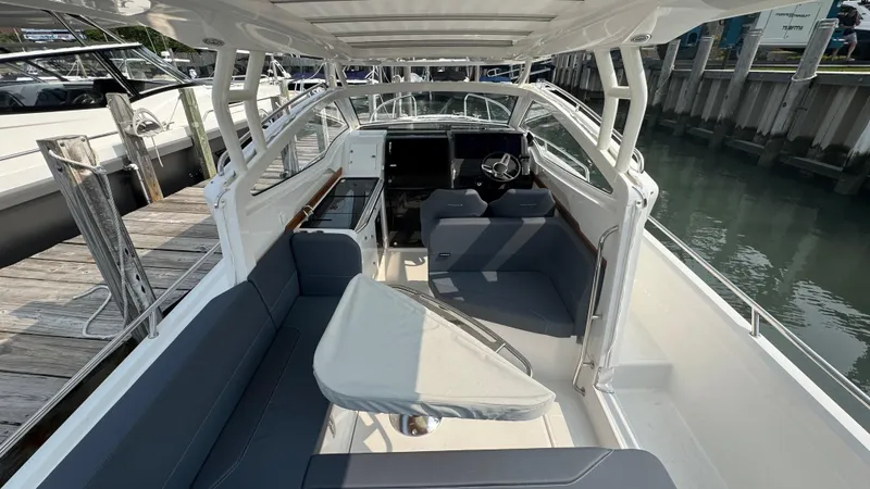Slide: The Image of 2024 Nimbus W9 boat interior with seating and steering, docked by the water. - 6