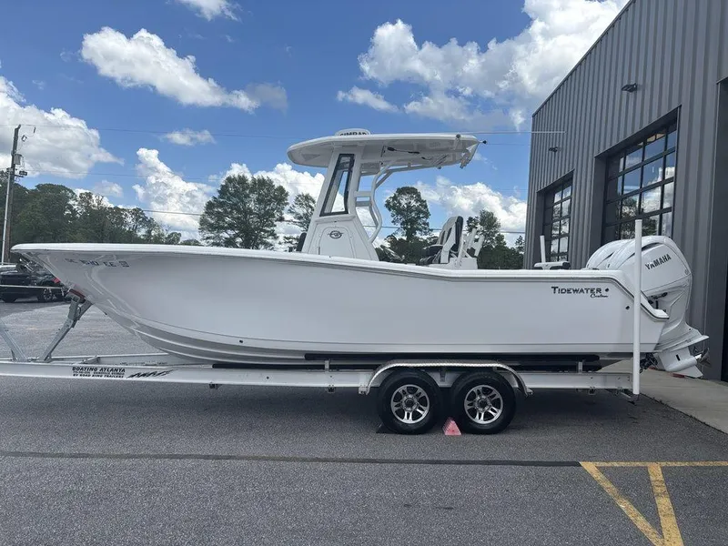 Slide: The Image of 2024 Tidewater 256 CC Adventure boat on trailer, parked outside a building under a cloudy sky. - 18