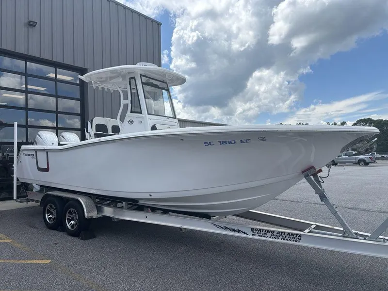 Slide: The Image of 2024 Tidewater 256 CC Adventure boat on trailer, parked outdoors under cloudy sky. - 22