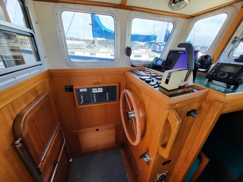 Slide: The Image of 1978 Fisher 25 boat interior with wooden helm, navigation equipment, and windows overlooking marina. - 10