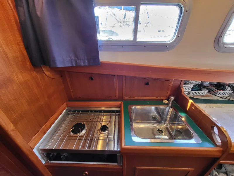Slide: The Image of 1978 Fisher 25 boat kitchen with stove and sink, wooden cabinetry, and window view. - 12
