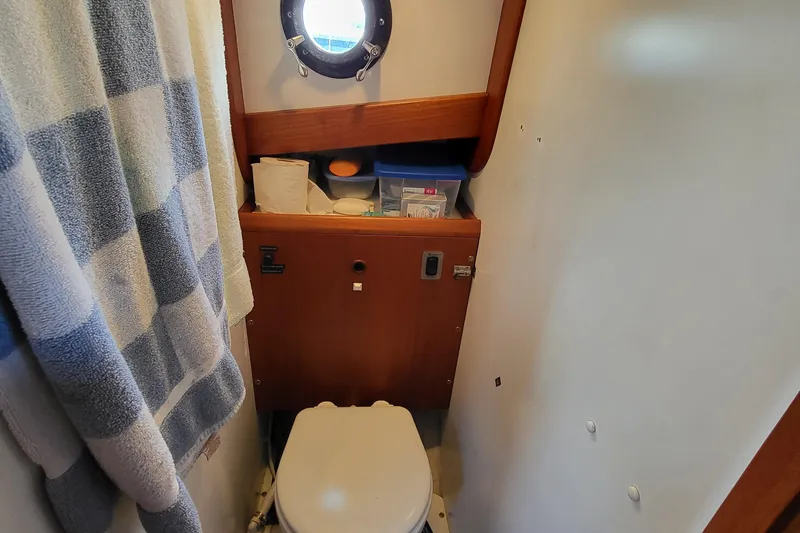 Slide: The Image of 1978 Fisher 25 boat bathroom with porthole, toilet, and storage shelves. - 14
