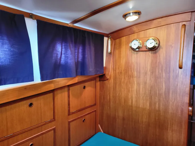 Slide: The Image of 1978 Fisher 25 cabin interior with wooden paneling and blue curtains. - 16