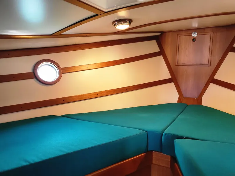 Slide: The Image of 1978 Fisher 25 boat cabin with teal cushions, wooden accents, and a porthole window. - 21