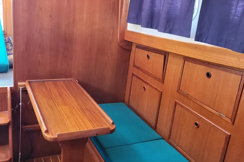 Slide: The Image of Interior of a 1978 Fisher 25 boat with wooden table, teal cushions, and storage drawers. - 24