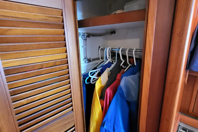 Slide: The Image of Wooden closet with colorful jackets on hangers inside a 1978 Fisher 25 boat. - 25