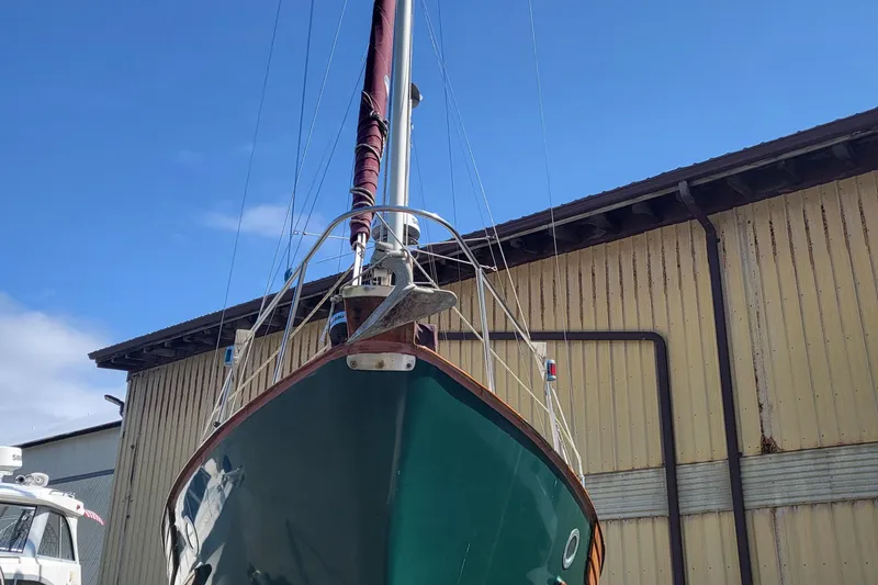 Slide: The Image of 1978 Fisher 25 sailboat with green hull, docked near a warehouse under a clear blue sky. - 33