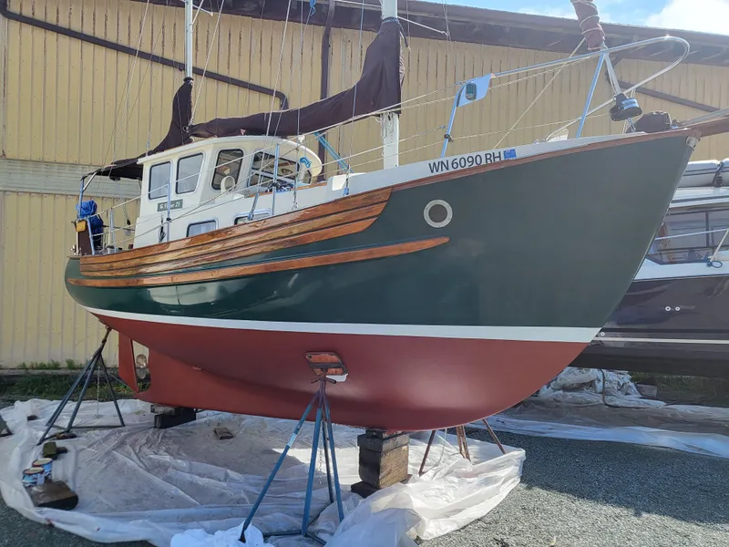 Slide: The Image of 1978 Fisher 25 sailboat on stands, green hull with wooden accents, in a boatyard. - 34