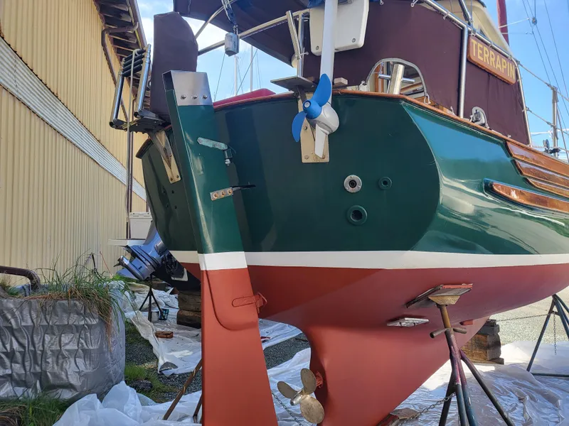 Slide: The Image of 1978 Fisher 25 sailboat on stands, showcasing its green and red hull and rudder. - 36