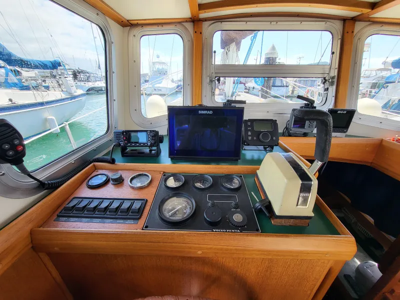 Slide: The Image of 1978 Fisher 25 boat cockpit with navigation instruments and steering wheel, docked at marina. - 8