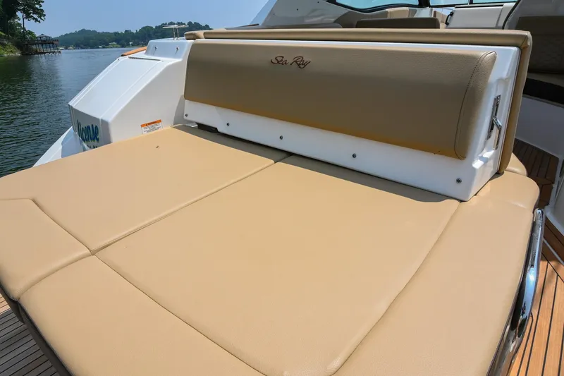 Slide: The Image of 2020 Sea Ray Sundancer 320 Coupe with tan sunpad on deck, docked by a lake. - 9