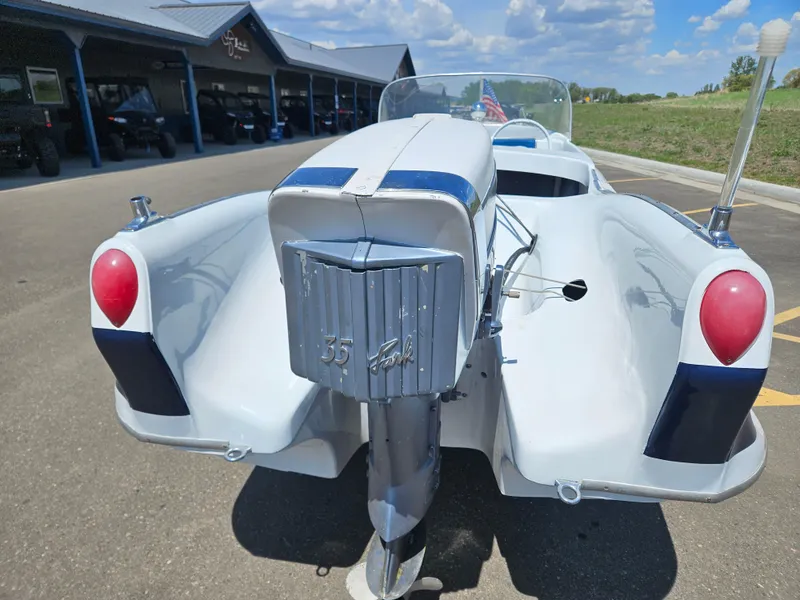 Slide: The Image of 1958 Larson Falls Flyer boat with vintage design, parked outdoors under a blue sky. - 10
