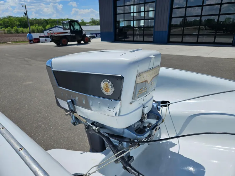 Slide: The Image of 1958 Larson Falls Flyer boat engine, outdoor setting, sunny day, industrial background. - 9