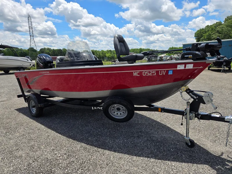 Slide: The Image of 2022 Lund 1775 Adventure SS boat on trailer, red and black, parked outdoors. - 2