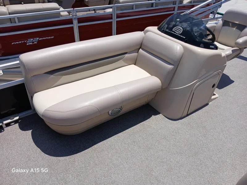 Slide: The Image of 2015 Sun Tracker Fishin Barge 24 DLX, beige seating and console, outdoor setting. - 11
