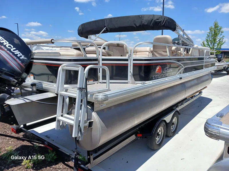 Slide: The Image of 2015 Sun Tracker Fishin Barge 24 DLX pontoon boat on trailer, with Mercury outboard motor. - 3