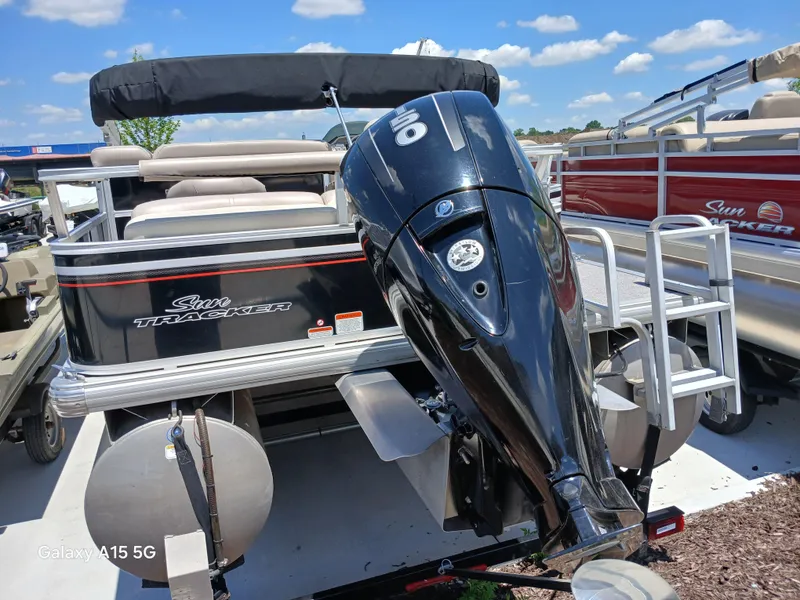 Slide: The Image of 2015 Sun Tracker Fishin Barge 24 DLX with outboard motor, docked under blue sky. - 4