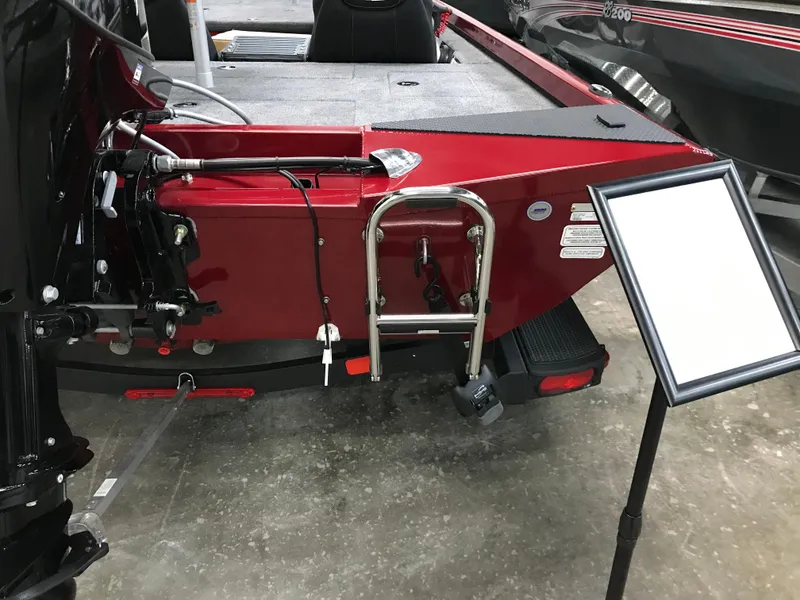 Slide: The Image of 2025 Ranger RT178C boat, red exterior, rear view with ladder and motor, displayed indoors. - 7