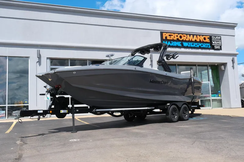 The Image of 2025 MasterCraft X26 boat on trailer outside Performance Marine Watersports store. - 1