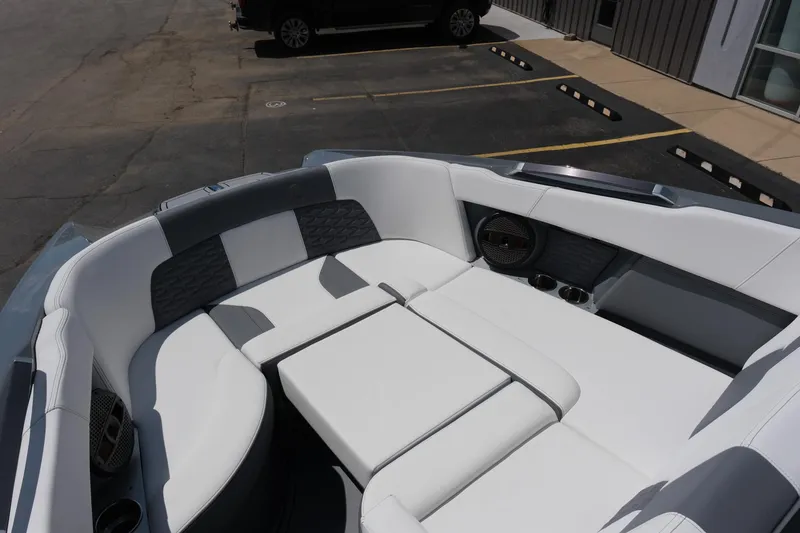Slide: The Image of 2025 MasterCraft X26 boat interior with white and gray seating in a parking lot. - 30