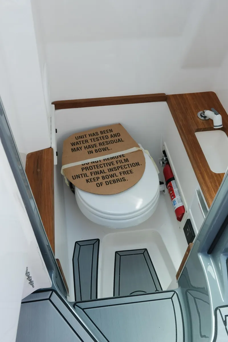Slide: The Image of 2025 MasterCraft X26 boat bathroom with toilet, sink, and safety instructions. - 33