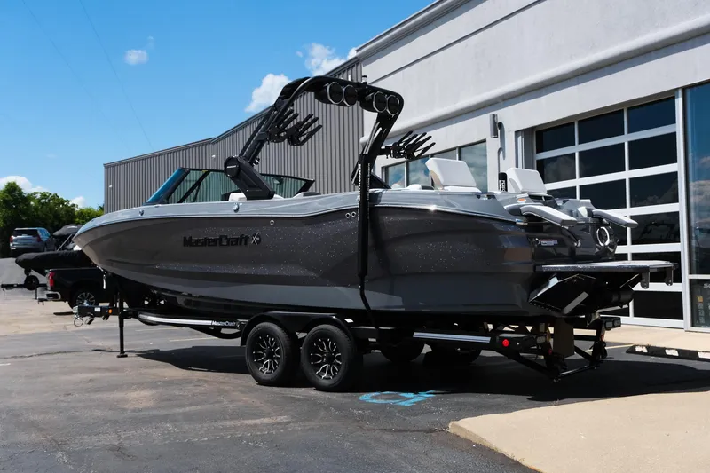 Slide: The Image of 2025 MasterCraft X26 boat on trailer, parked outside a building under a clear blue sky. - 4