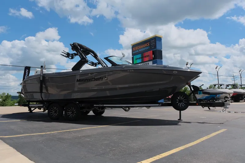 Slide: The Image of 2025 MasterCraft X26 boat on trailer under cloudy sky at dealership. - 9