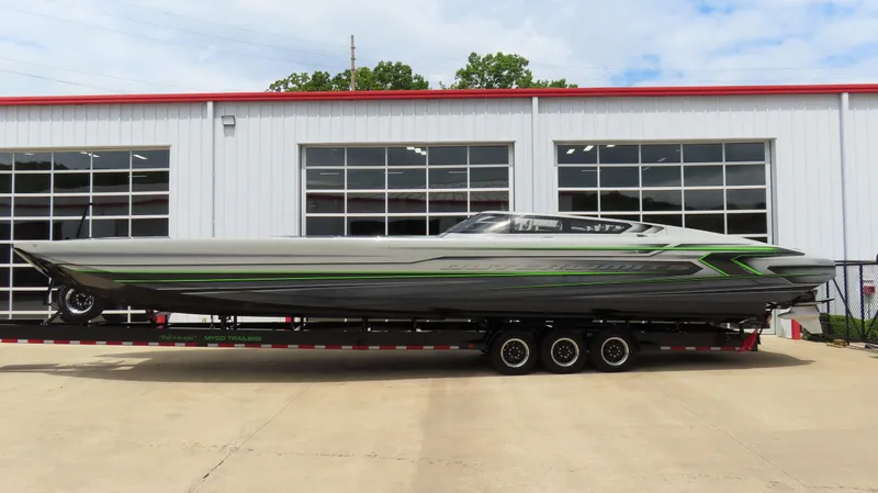 The Image of 2025 Outerlimits 46 SC powerboat on trailer, sleek design with green accents, parked outside a garage. - 0
