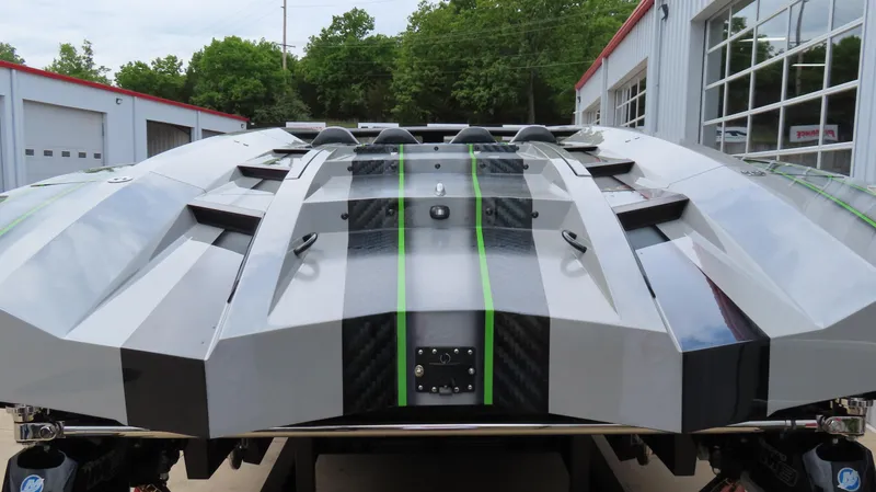 Slide: The Image of 2025 Outerlimits 46 SC powerboat with sleek design and green accents, parked outdoors. - 11