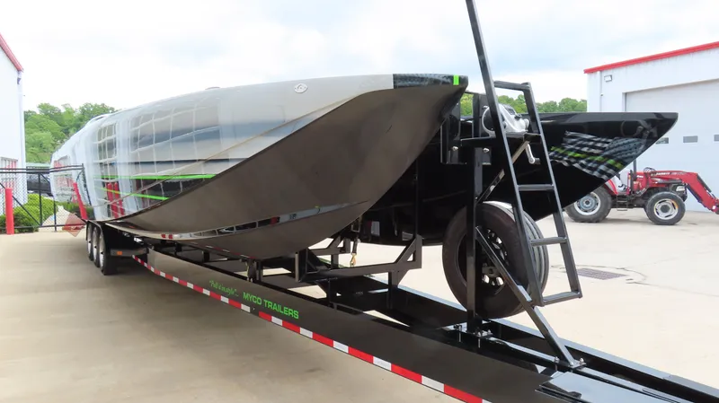 Slide: The Image of 2025 Outerlimits 46 SC powerboat on trailer, sleek design, parked outdoors. - 6