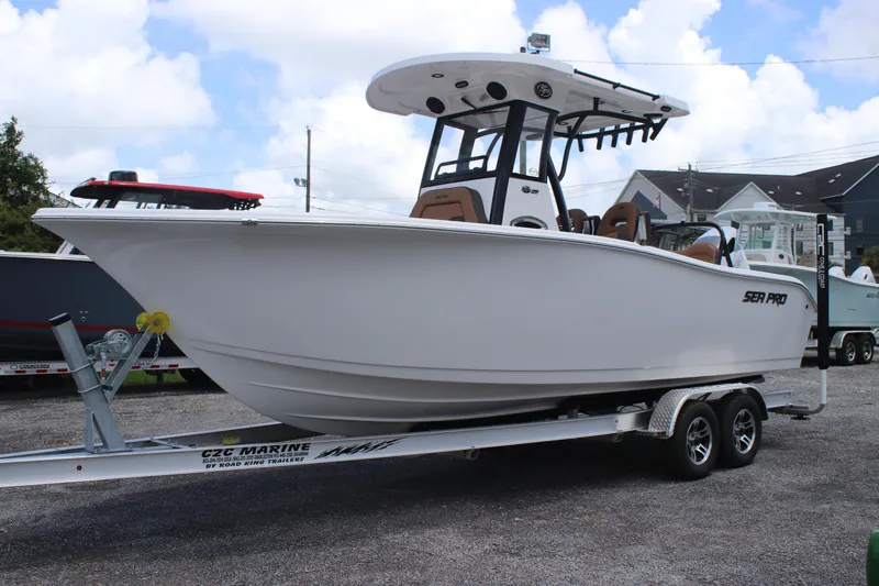 Slide: The Image of 2025 Sea Pro 245 FLX boat on trailer, parked outdoors under cloudy sky. - 2