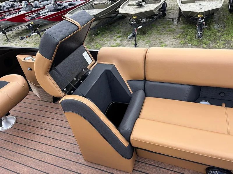Slide: The Image of 2025 Bentley Pontoons Elite 253 Swingback interior with tan and black seating, open storage compartment. - 13
